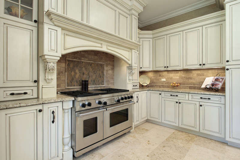 Inredning av ett klassiskt avskilt, mellanstort l-kök, med en undermonterad diskho, luckor med upphöjd panel, vita skåp, granitbänkskiva, beige stänkskydd, stänkskydd i stenkakel, rostfria vitvaror, mörkt trägolv, en köksö och brunt golv