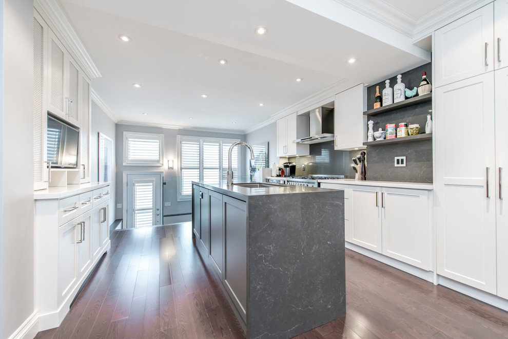 Photo of a large modern u-shaped enclosed kitchen in Toronto with shaker cabinets, white cabinets, grey splashback, stainless steel appliances, dark hardwood flooring and an island.