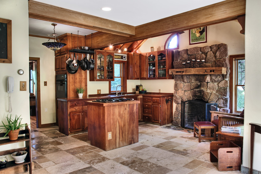 Exemple d'une petite cuisine américaine chic en L et bois foncé avec un évier encastré, un placard avec porte à panneau encastré, un plan de travail en bois, un électroménager noir, un sol en travertin, îlot et un sol beige.
