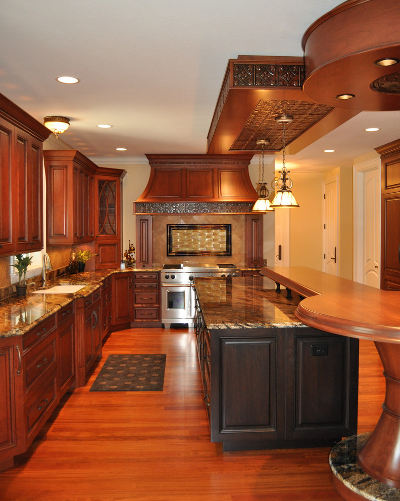 Example of a large classic l-shaped medium tone wood floor open concept kitchen design in Cleveland with an undermount sink, raised-panel cabinets, medium tone wood cabinets, granite countertops, beige backsplash, ceramic backsplash, stainless steel appliances, an island and multicolored countertops
