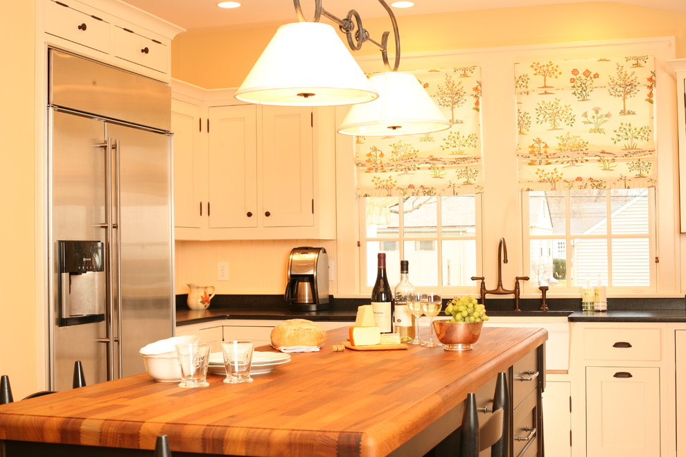 На фото: кухня в классическом стиле с с полувстраиваемой мойкой (с передним бортиком), деревянной столешницей, белыми фасадами и барной стойкой с