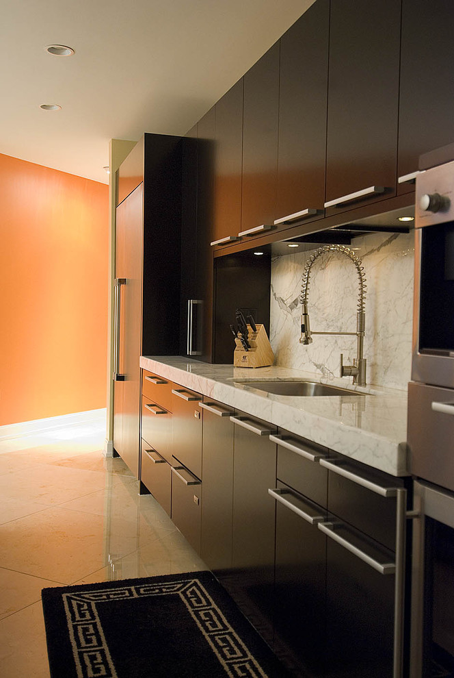 Bild på ett funkis kök, med rostfria vitvaror, marmorbänkskiva, en undermonterad diskho, släta luckor, svarta skåp, vitt stänkskydd och stänkskydd i sten