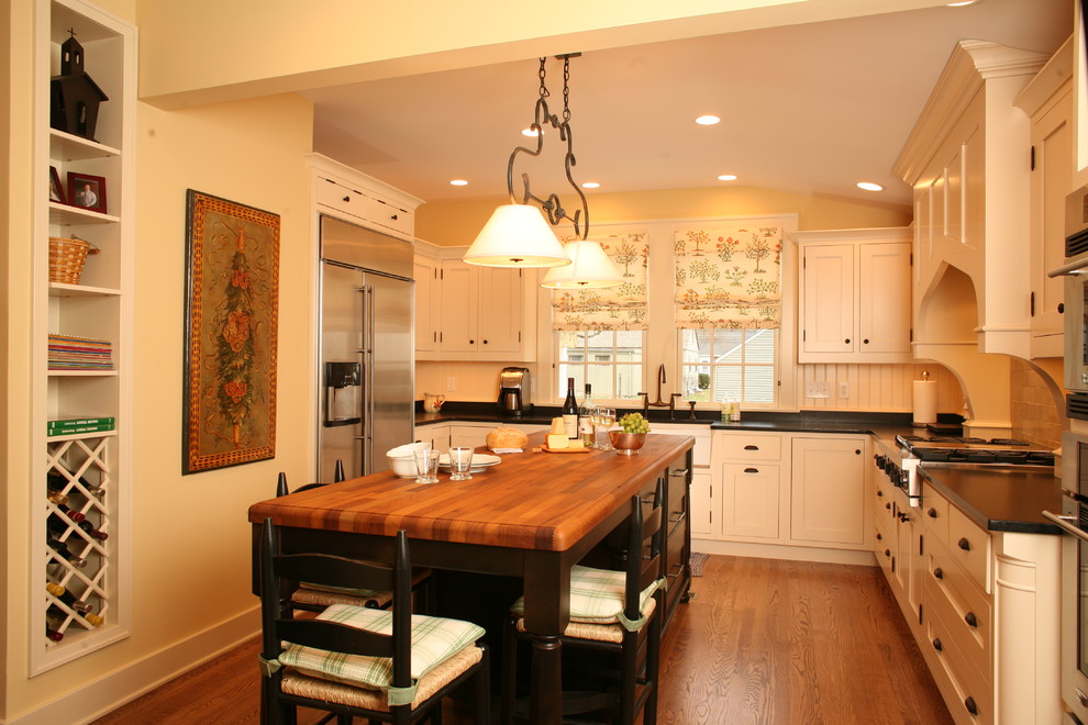 Стильный дизайн: п-образная кухня в классическом стиле с деревянной столешницей, белыми фасадами и барной стойкой - последний тренд