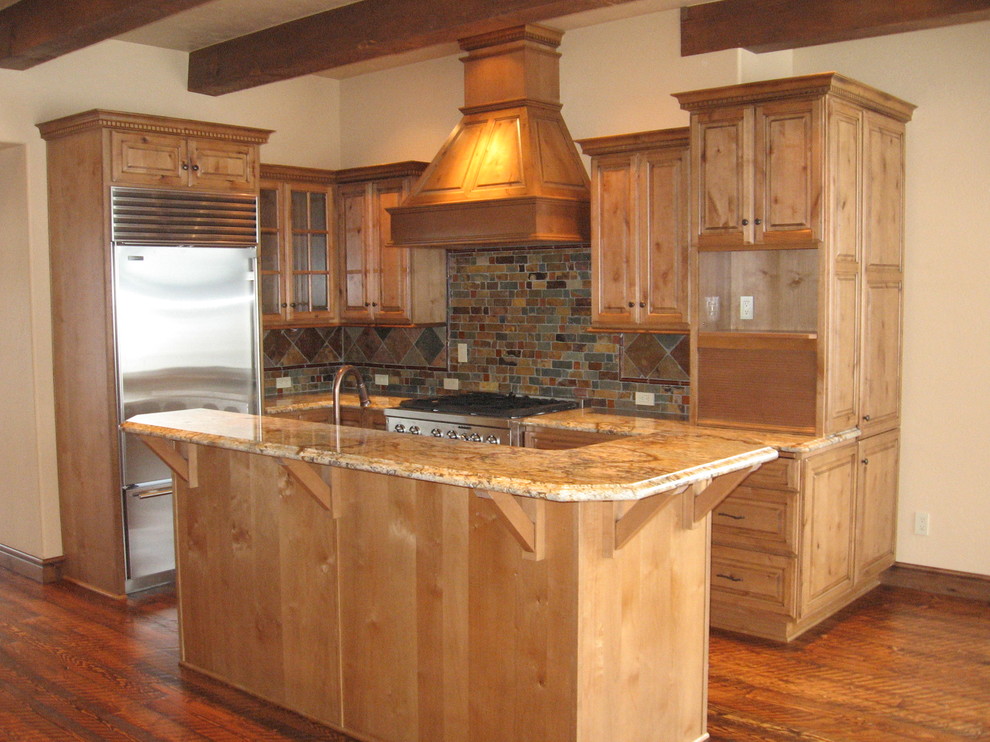 Eat-in kitchen - small traditional l-shaped medium tone wood floor eat-in kitchen idea in Denver with an undermount sink, raised-panel cabinets, medium tone wood cabinets, granite countertops, multicolored backsplash, stone tile backsplash, stainless steel appliances and an island