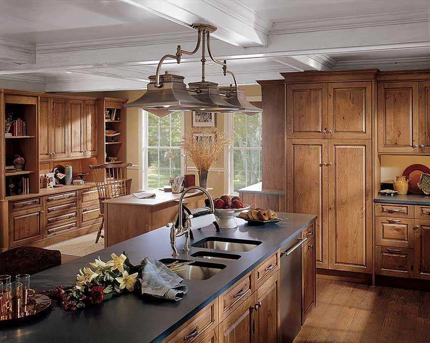Inredning av ett amerikanskt mellanstort kök, med en trippel diskho, luckor med upphöjd panel, skåp i mellenmörkt trä, bänkskiva i koppar, rostfria vitvaror, mellanmörkt trägolv och en köksö