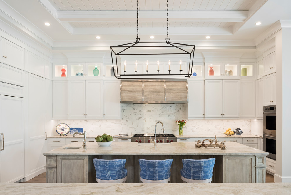 This is an example of a beach style u-shaped kitchen in Other with stainless steel appliances, an island, recessed-panel cabinets, yellow cabinets and white splashback.