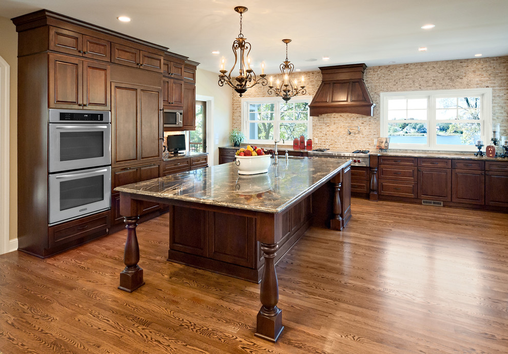 Kitchen - traditional kitchen idea in Minneapolis with raised-panel cabinets, dark wood cabinets, beige backsplash and paneled appliances