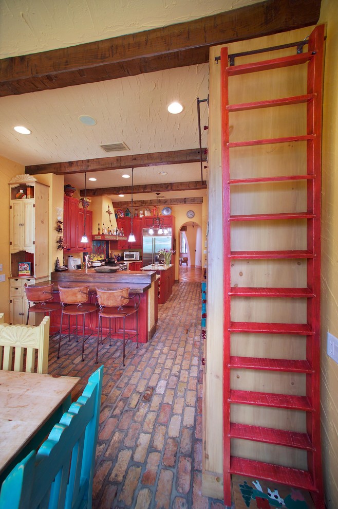 Aménagement d'une cuisine sud-ouest américain avec des portes de placard rouges et un sol en brique.