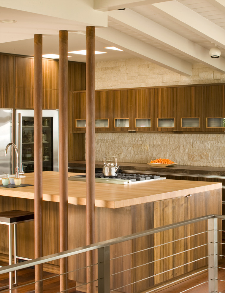 Bild på ett 60 tals kök, med träbänkskiva, släta luckor, skåp i mörkt trä, beige stänkskydd, stänkskydd i stenkakel och rostfria vitvaror