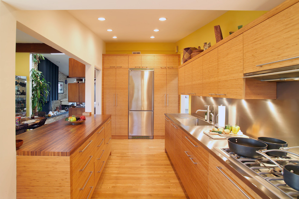 Foto på ett funkis kök, med rostfria vitvaror, bänkskiva i rostfritt stål, en integrerad diskho, stänkskydd med metallisk yta och stänkskydd i metallkakel