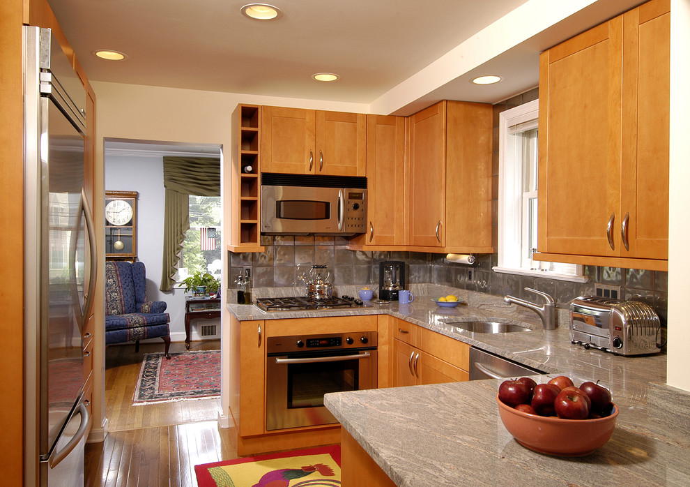Exempel på ett klassiskt u-kök, med granitbänkskiva, rostfria vitvaror och stänkskydd med metallisk yta