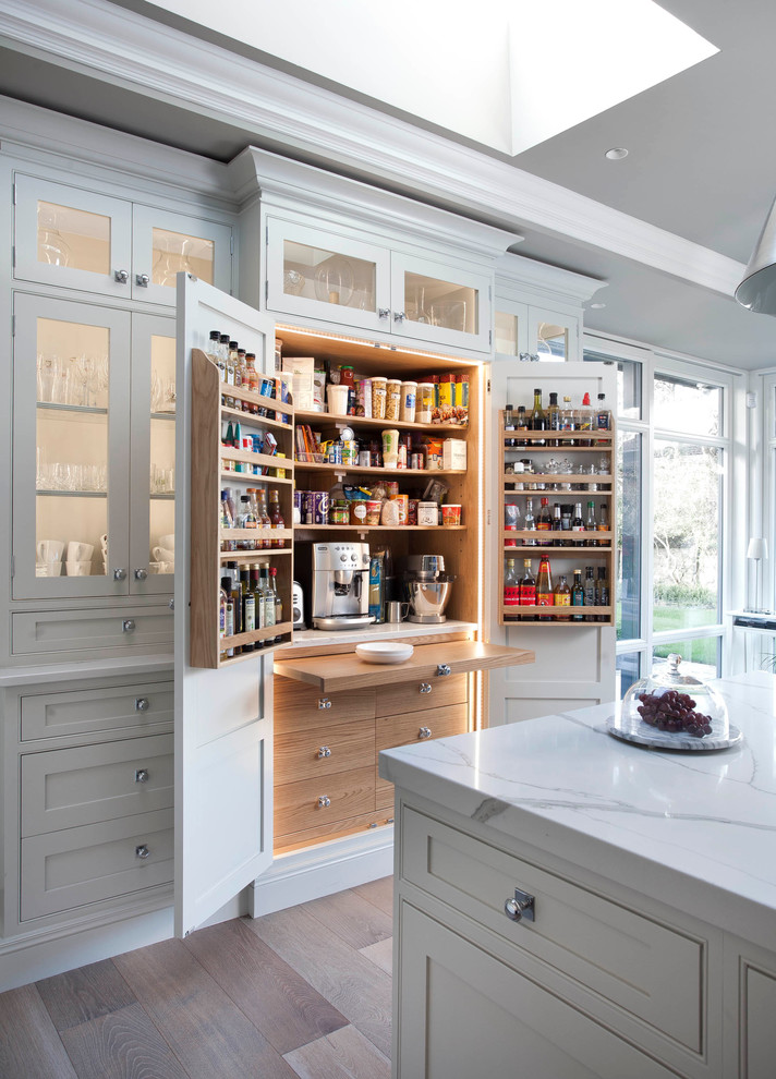 Design ideas for a traditional kitchen pantry in Dublin with flat-panel cabinets, light wood cabinets and light hardwood flooring.
