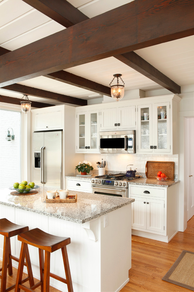 Inspiration for a small timeless medium tone wood floor and brown floor eat-in kitchen remodel in Other with white cabinets, white backsplash, ceramic backsplash, stainless steel appliances, an island, granite countertops and shaker cabinets