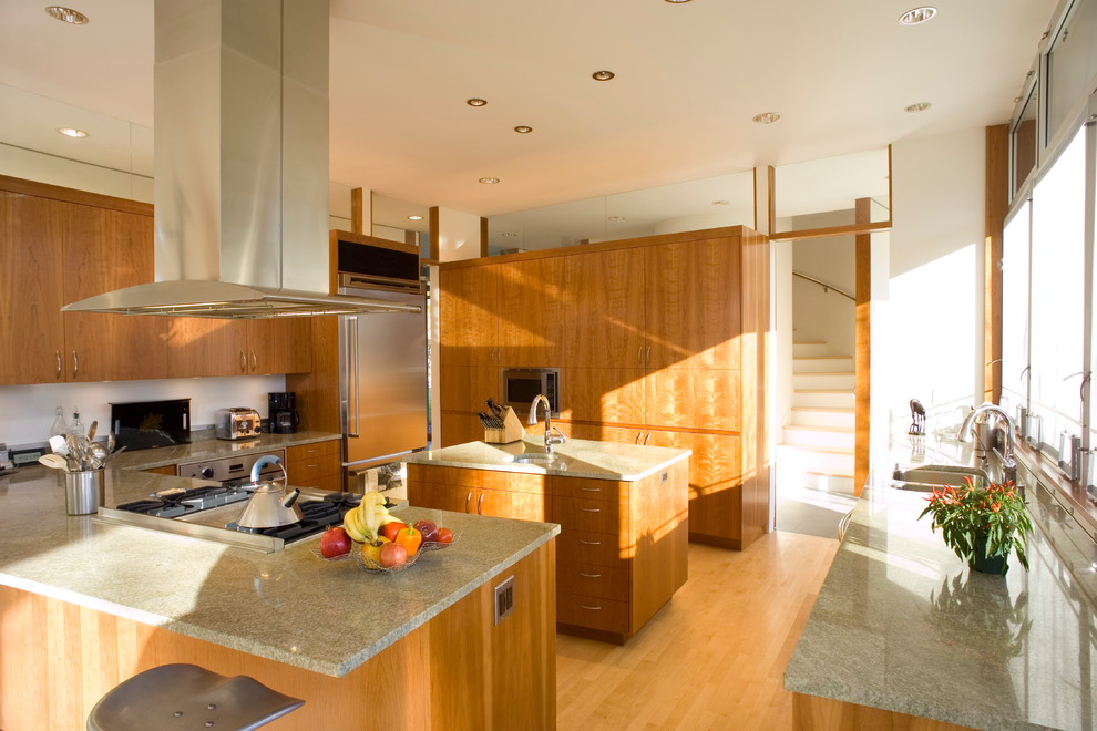 Exempel på ett stort modernt kök, med en undermonterad diskho, släta luckor, skåp i mellenmörkt trä, granitbänkskiva, vitt stänkskydd, rostfria vitvaror, ljust trägolv, en köksö och brunt golv