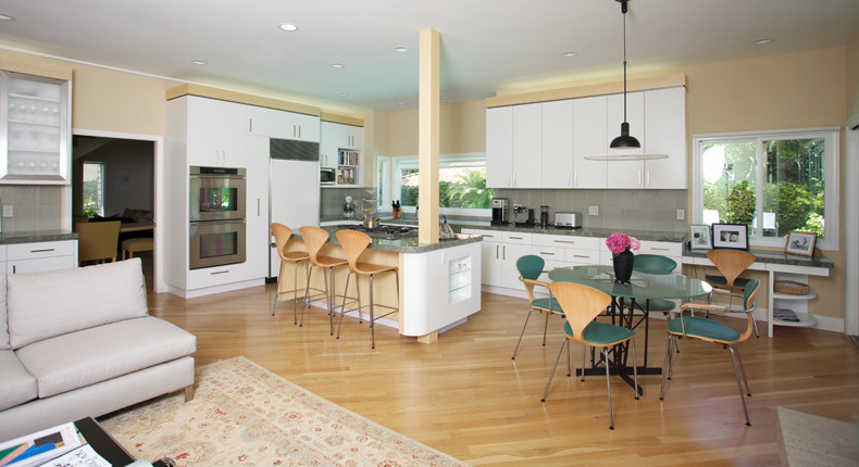 Foto på ett stort funkis kök, med vita skåp, grått stänkskydd, rostfria vitvaror, ljust trägolv, en köksö, släta luckor, en enkel diskho och granitbänkskiva