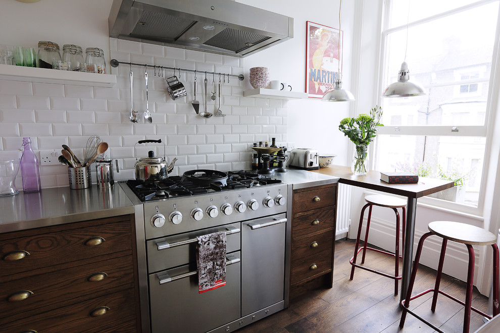 Einzeilige Klassische Küche mit dunklen Holzschränken, Edelstahl-Arbeitsplatte, Küchenrückwand in Weiß, Rückwand aus Metrofliesen, Küchengeräten aus Edelstahl, dunklem Holzboden und Halbinsel in London