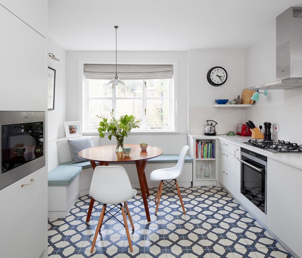 Example of a small trendy galley ceramic tile eat-in kitchen design in London with flat-panel cabinets, white cabinets and no island