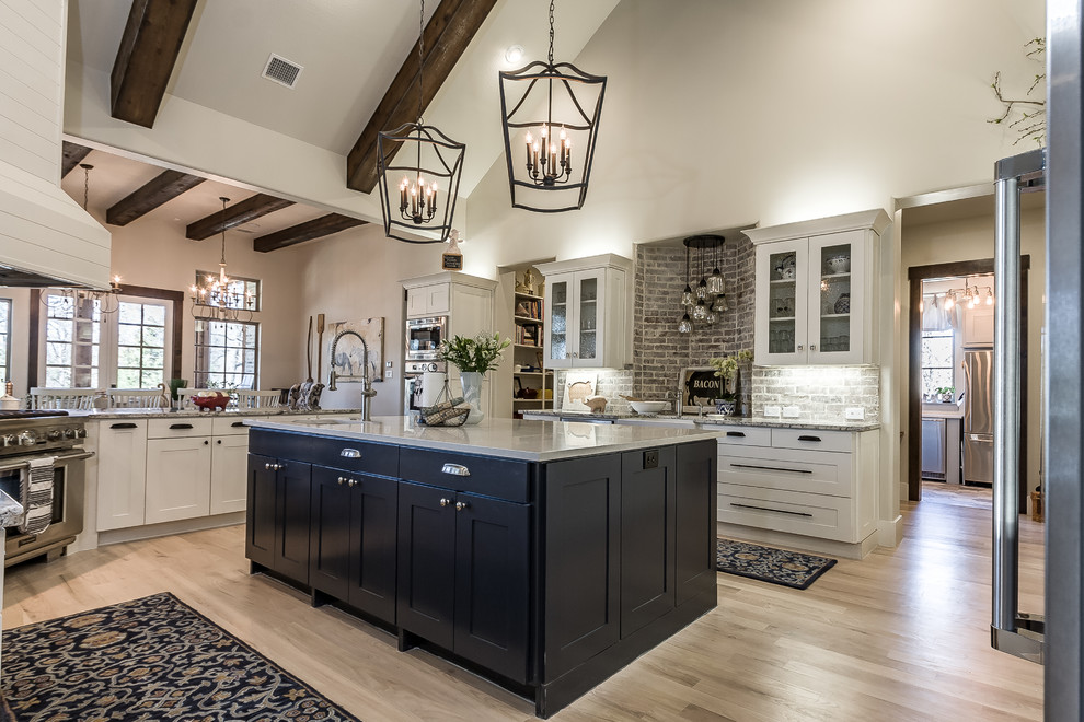 Inspiration for a farmhouse kitchen remodel in Dallas with white cabinets, brick backsplash and stainless steel appliances