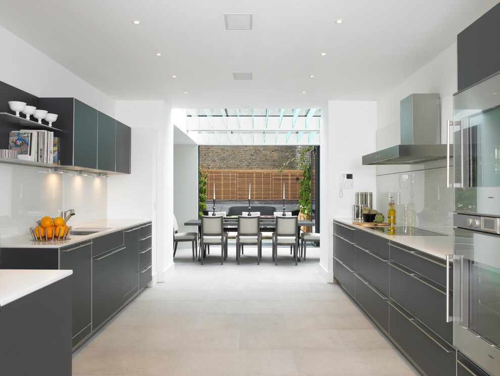 Eat-in kitchen - large contemporary galley eat-in kitchen idea in London with flat-panel cabinets, gray cabinets and white backsplash