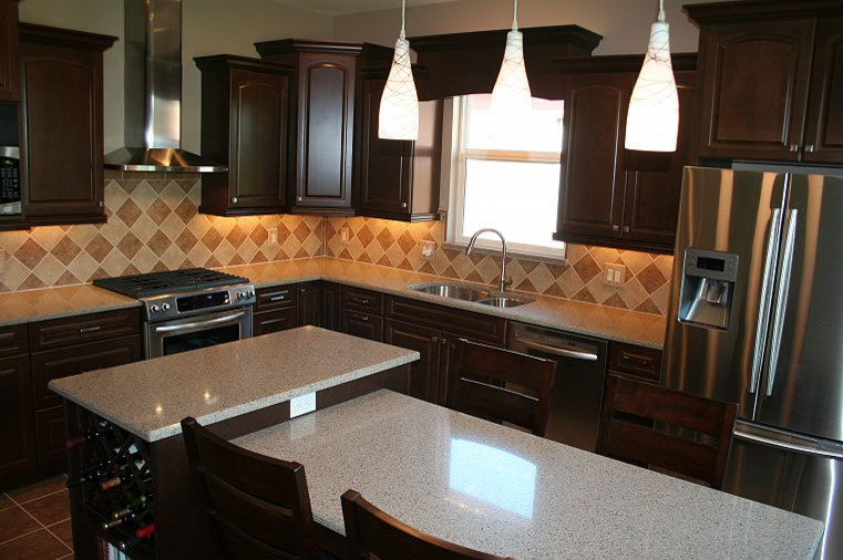 Bild på ett stort funkis kök, med en dubbel diskho, skåp i mörkt trä, granitbänkskiva, beige stänkskydd, stänkskydd i keramik, rostfria vitvaror, klinkergolv i keramik, flera köksöar och brunt golv