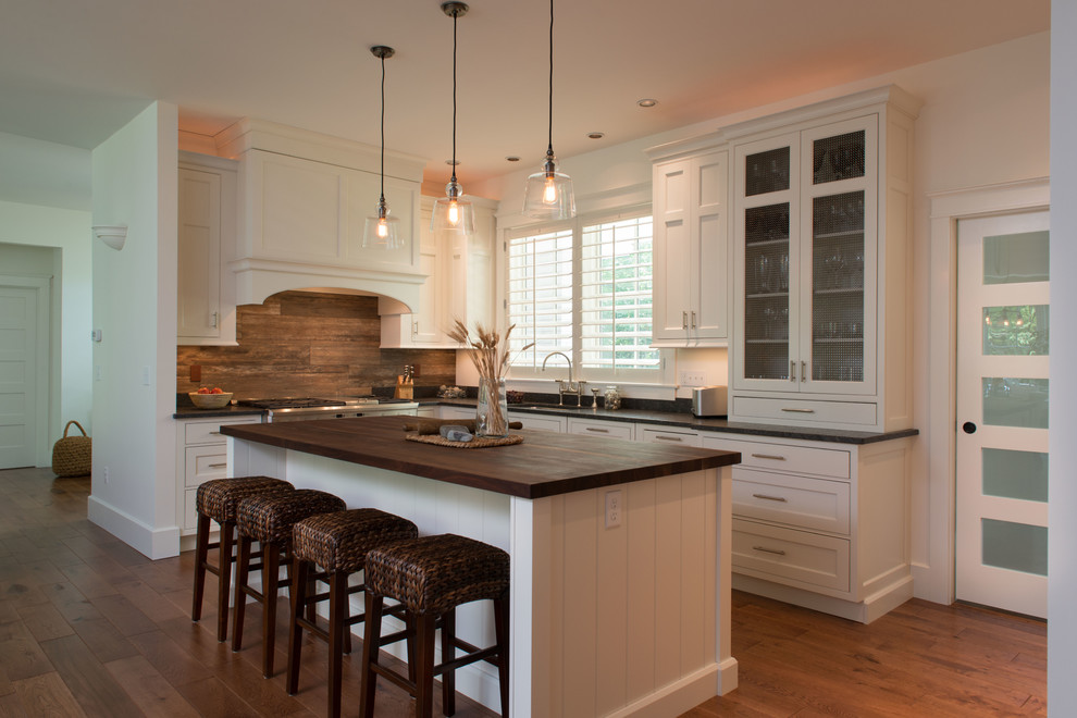 Example of a mid-sized transitional l-shaped light wood floor eat-in kitchen design in Boston with a single-bowl sink, recessed-panel cabinets, white cabinets, wood countertops, brown backsplash, glass sheet backsplash, stainless steel appliances and an island