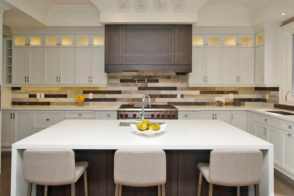 Photo of a medium sized traditional l-shaped kitchen in Toronto with a submerged sink, white cabinets, ceramic splashback, stainless steel appliances, dark hardwood flooring, an island, brown floors, shaker cabinets, multi-coloured splashback and white worktops.