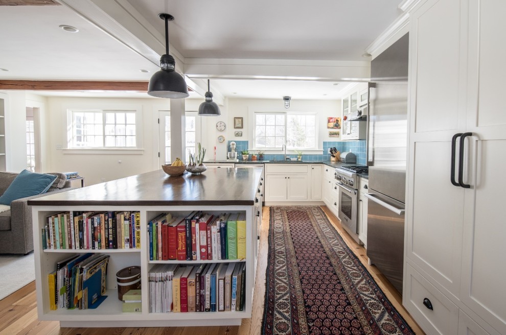 Klassisk inredning av ett mellanstort kök, med en undermonterad diskho, luckor med infälld panel, vita skåp, träbänkskiva, blått stänkskydd, stänkskydd i keramik, rostfria vitvaror, mellanmörkt trägolv och en köksö