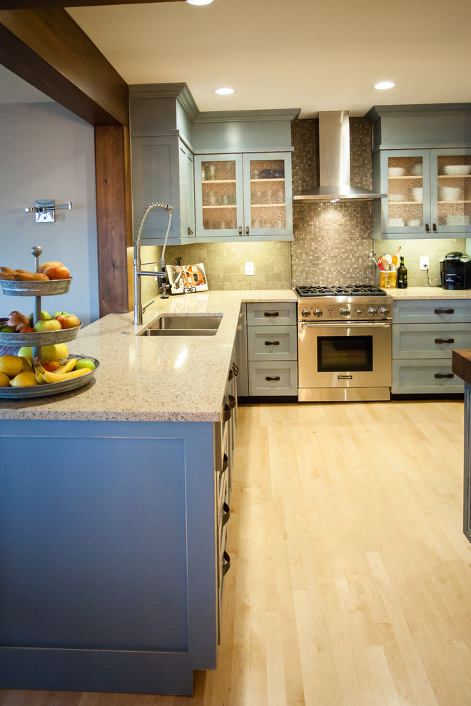 Photo of a medium sized country l-shaped open plan kitchen in Seattle with a submerged sink, shaker cabinets, blue cabinets, wood worktops, grey splashback, stone tiled splashback, stainless steel appliances, light hardwood flooring and an island.