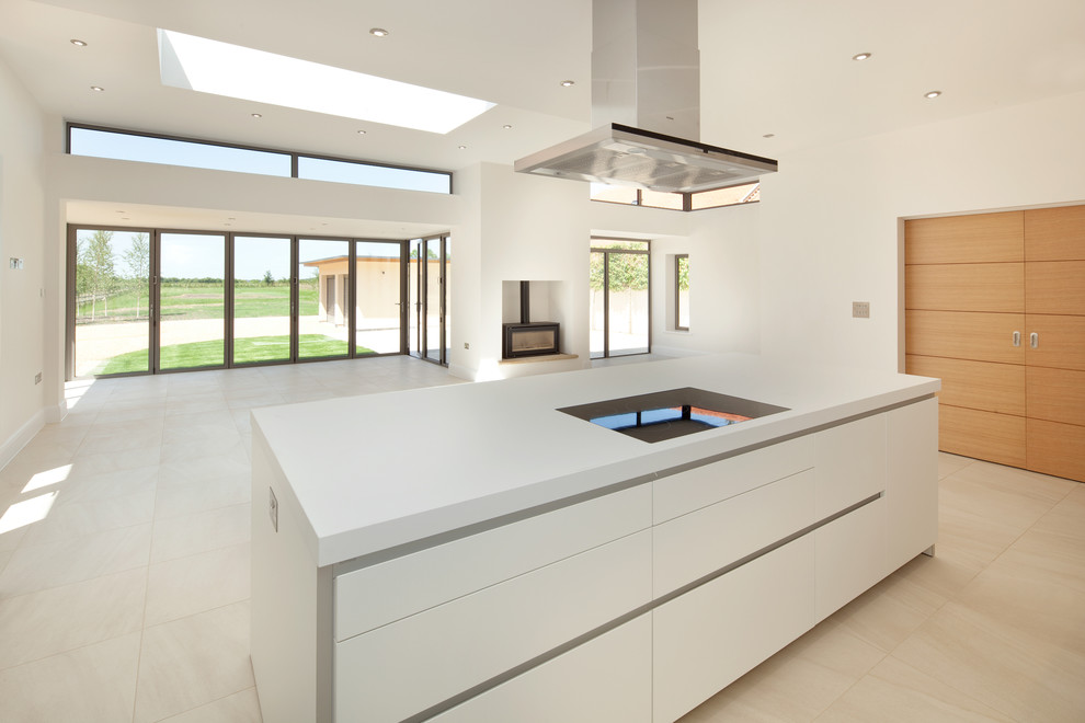 Inspiration for a large contemporary l-shaped kitchen/diner in Oxfordshire with a double-bowl sink, flat-panel cabinets, white cabinets, composite countertops, white splashback, stainless steel appliances, porcelain flooring and an island.
