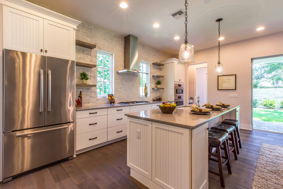Inspiration for a large farmhouse single-wall dark wood floor kitchen remodel in Orlando with white cabinets, granite countertops, stainless steel appliances, an undermount sink, flat-panel cabinets, gray backsplash and an island