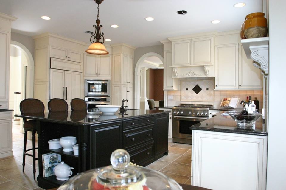 Example of an eclectic l-shaped porcelain tile eat-in kitchen design in Providence with an undermount sink, raised-panel cabinets, white cabinets, granite countertops, beige backsplash, porcelain backsplash, stainless steel appliances and an island