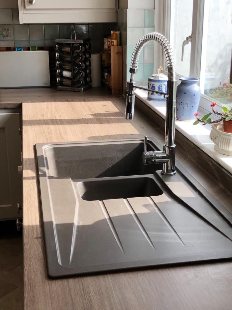 Modelo de cocina de estilo de casa de campo con fregadero encastrado, armarios estilo shaker, puertas de armario grises, encimera de laminado, suelo vinílico, suelo gris y encimeras marrones