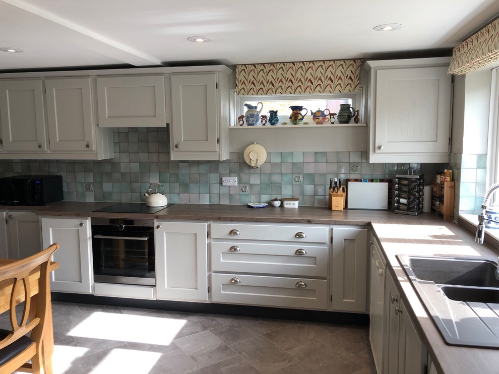 This is an example of a country kitchen in Oxfordshire with a built-in sink, shaker cabinets, grey cabinets, laminate countertops, vinyl flooring, grey floors and brown worktops.