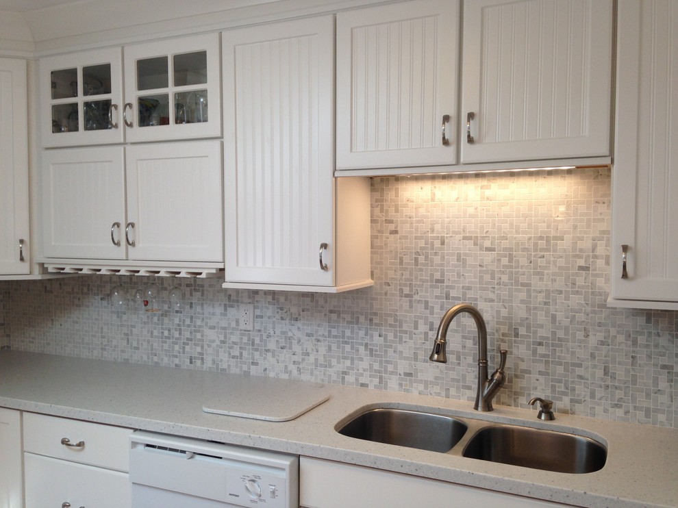 Example of a mid-sized beach style l-shaped eat-in kitchen design in Other with an undermount sink, beaded inset cabinets, white cabinets, solid surface countertops, gray backsplash, mosaic tile backsplash, white appliances and a peninsula