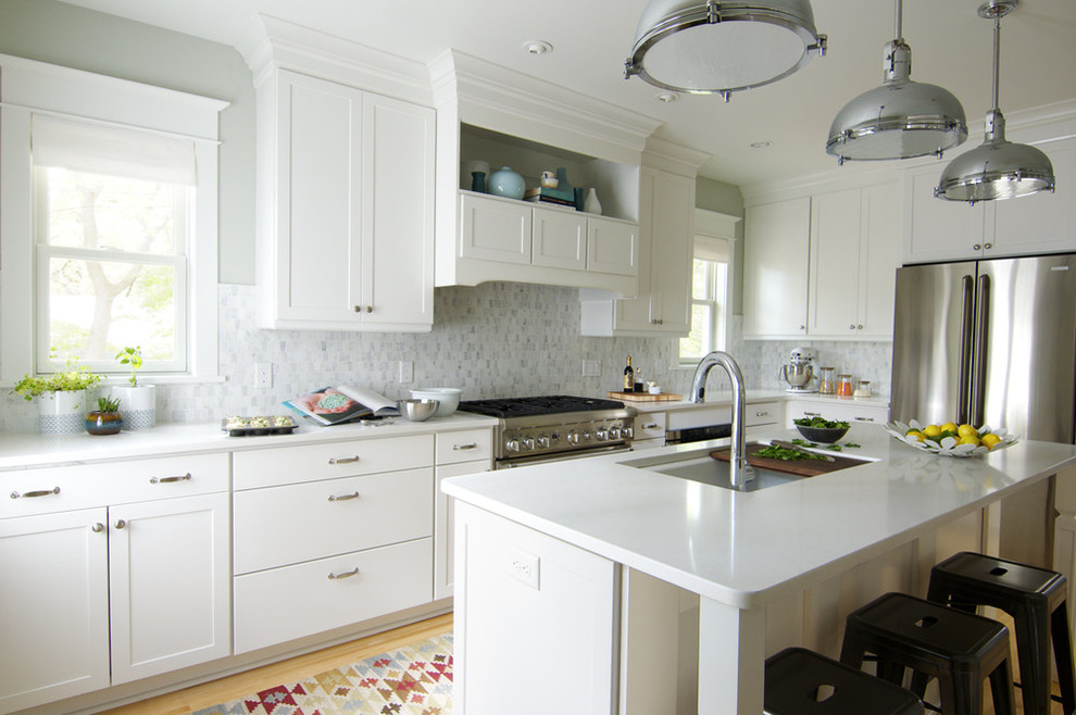 Photo of a traditional l-shaped kitchen/diner in Minneapolis with a submerged sink, flat-panel cabinets, white cabinets, composite countertops, grey splashback, stone tiled splashback and stainless steel appliances.