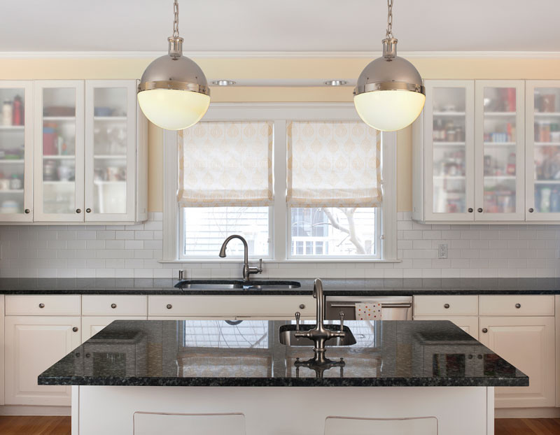 Klassische Küche mit weißen Schränken, Rückwand aus Metrofliesen, Küchengeräten aus Edelstahl und braunem Holzboden in Boston
