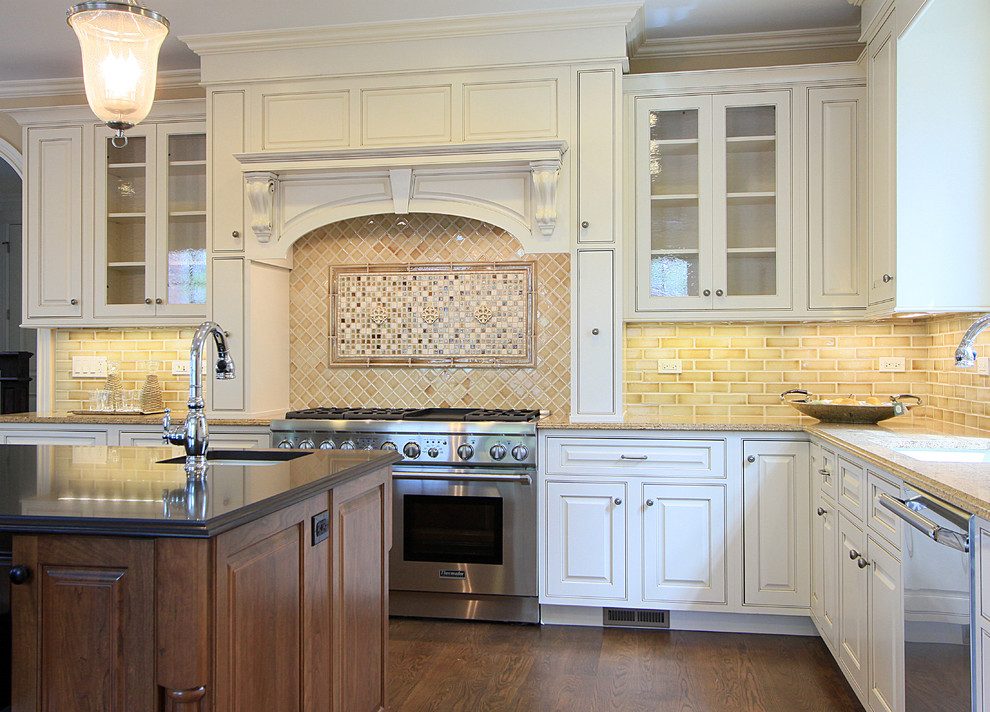 Exemple d'une cuisine bicolore chic avec un placard à porte affleurante, un électroménager en acier inoxydable, des portes de placard blanches, une crédence marron et une crédence en carrelage métro.