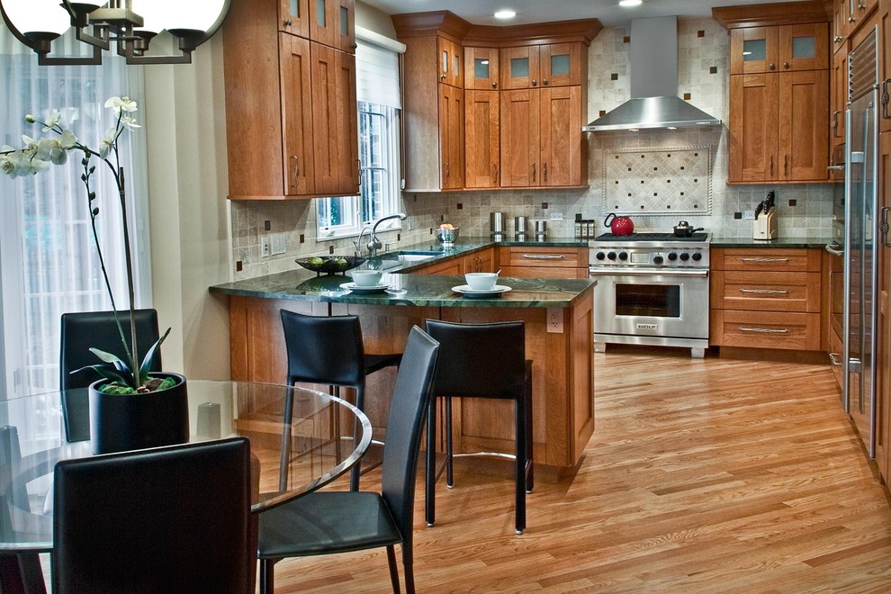 На фото: п-образная кухня в классическом стиле с обеденным столом, врезной мойкой, фасадами в стиле шейкер, фасадами цвета дерева среднего тона, серым фартуком и техникой из нержавеющей стали