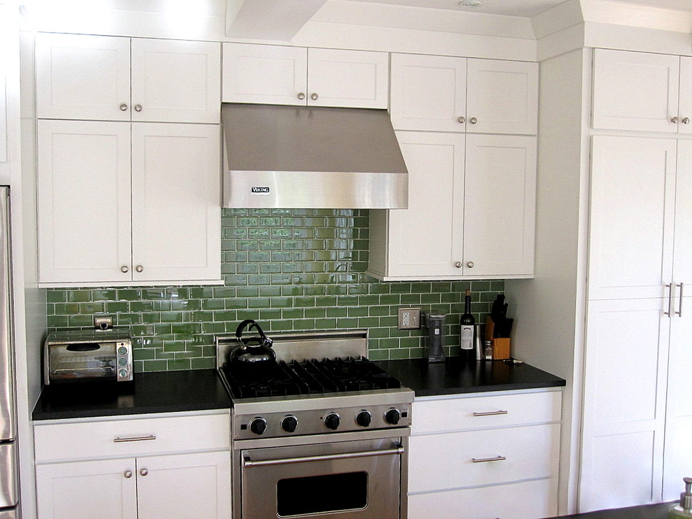 Modelo de cocina lineal de estilo americano de tamaño medio con puertas de armario blancas, salpicadero gris, salpicadero de azulejos tipo metro, electrodomésticos de acero inoxidable y una isla