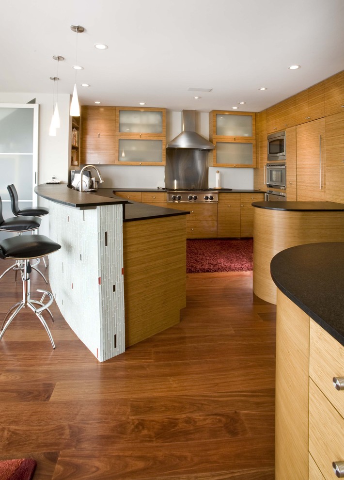 Inspiration pour une cuisine design avec un placard à porte plane, un électroménager en acier inoxydable et un sol en bois brun.