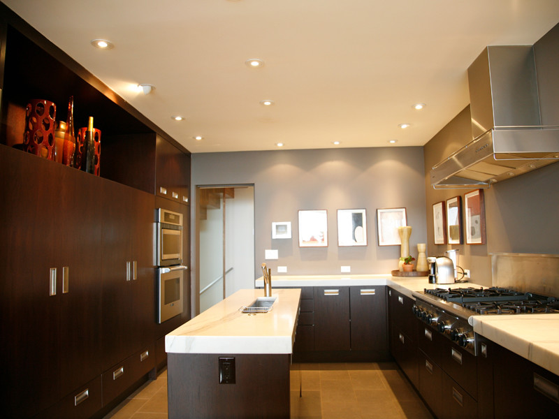 Bild på ett funkis kök, med skåp i mörkt trä, marmorbänkskiva, rostfria vitvaror och en köksö