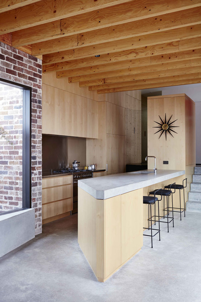 Offene Moderne Küche mit integriertem Waschbecken, hellen Holzschränken, Betonarbeitsplatte, Küchenrückwand in Metallic, Elektrogeräten mit Frontblende, Betonboden und Kücheninsel in Sydney
