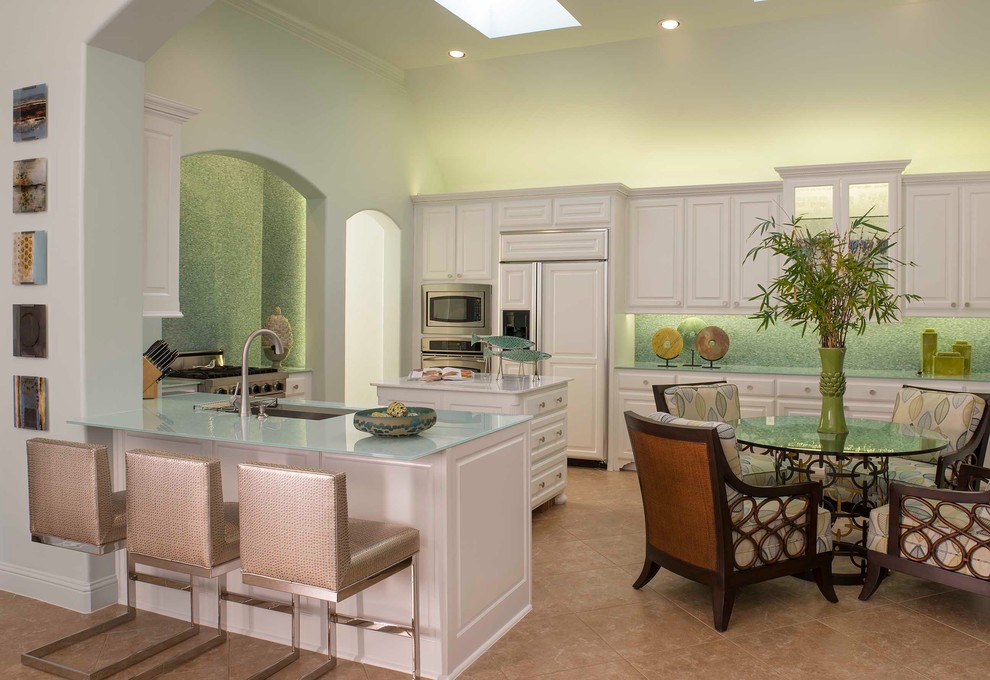 Mid-sized trendy u-shaped ceramic tile eat-in kitchen photo in Dallas with a drop-in sink, recessed-panel cabinets, white cabinets, glass countertops, green backsplash, mosaic tile backsplash, stainless steel appliances and an island