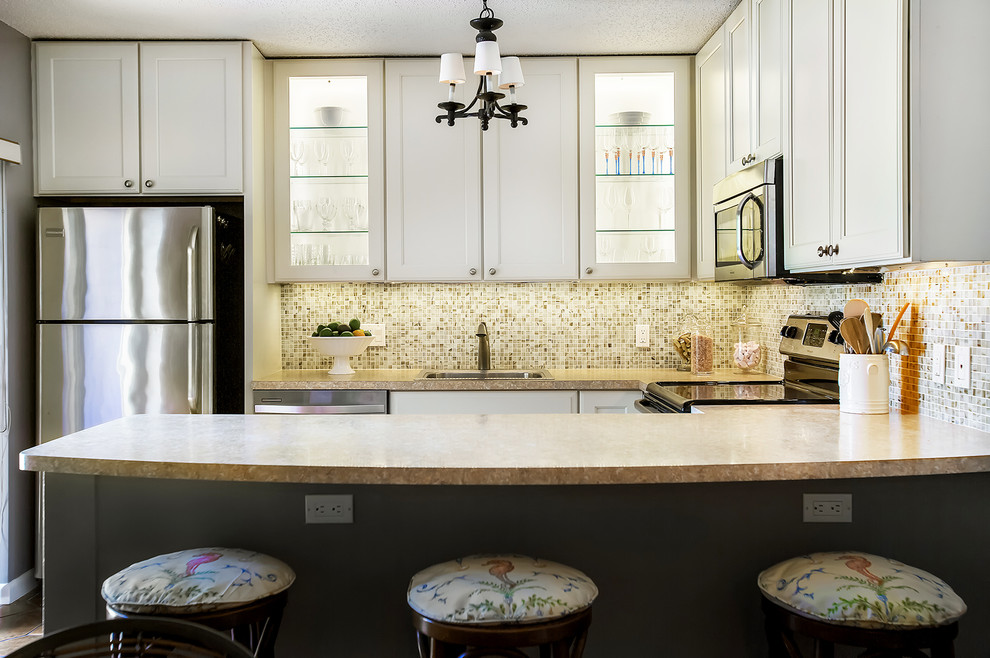 Bild på ett litet tropiskt beige beige kök, med en nedsänkt diskho, luckor med infälld panel, vita skåp, laminatbänkskiva, flerfärgad stänkskydd, stänkskydd i mosaik, rostfria vitvaror och en halv köksö