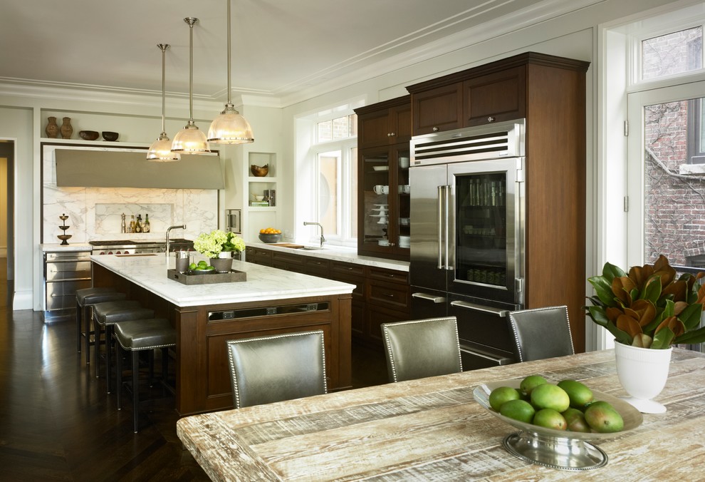 Пример оригинального дизайна: угловая кухня в классическом стиле с обеденным столом, фасадами с утопленной филенкой, темными деревянными фасадами, белым фартуком и фартуком из каменной плиты