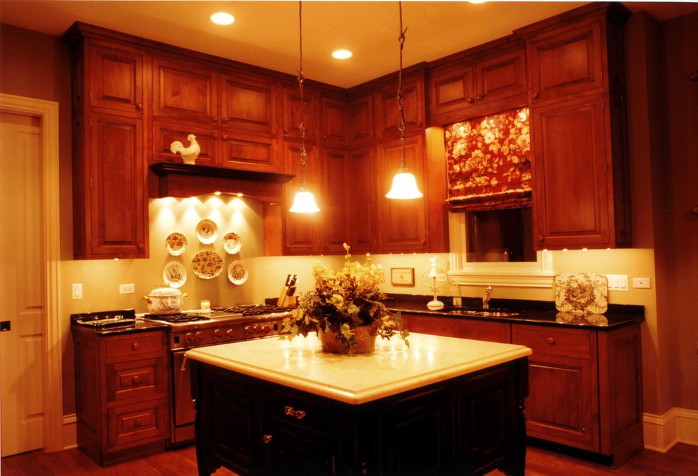 Farmhouse u-shaped medium tone wood floor eat-in kitchen photo in Chicago with an undermount sink, raised-panel cabinets, dark wood cabinets, black backsplash, stone slab backsplash, stainless steel appliances and an island