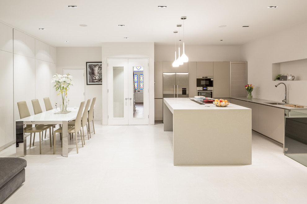 This is an example of an expansive contemporary open plan kitchen in London with an integrated sink, flat-panel cabinets, grey cabinets, concrete worktops, white splashback, stainless steel appliances, porcelain flooring and an island.
