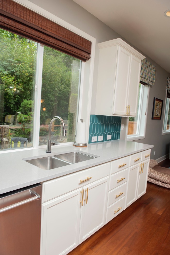 Exempel på ett stort 50 tals grå grått kök, med en undermonterad diskho, skåp i shakerstil, vita skåp, bänkskiva i kvartsit, grönt stänkskydd, stänkskydd i glaskakel, rostfria vitvaror, mellanmörkt trägolv och en köksö
