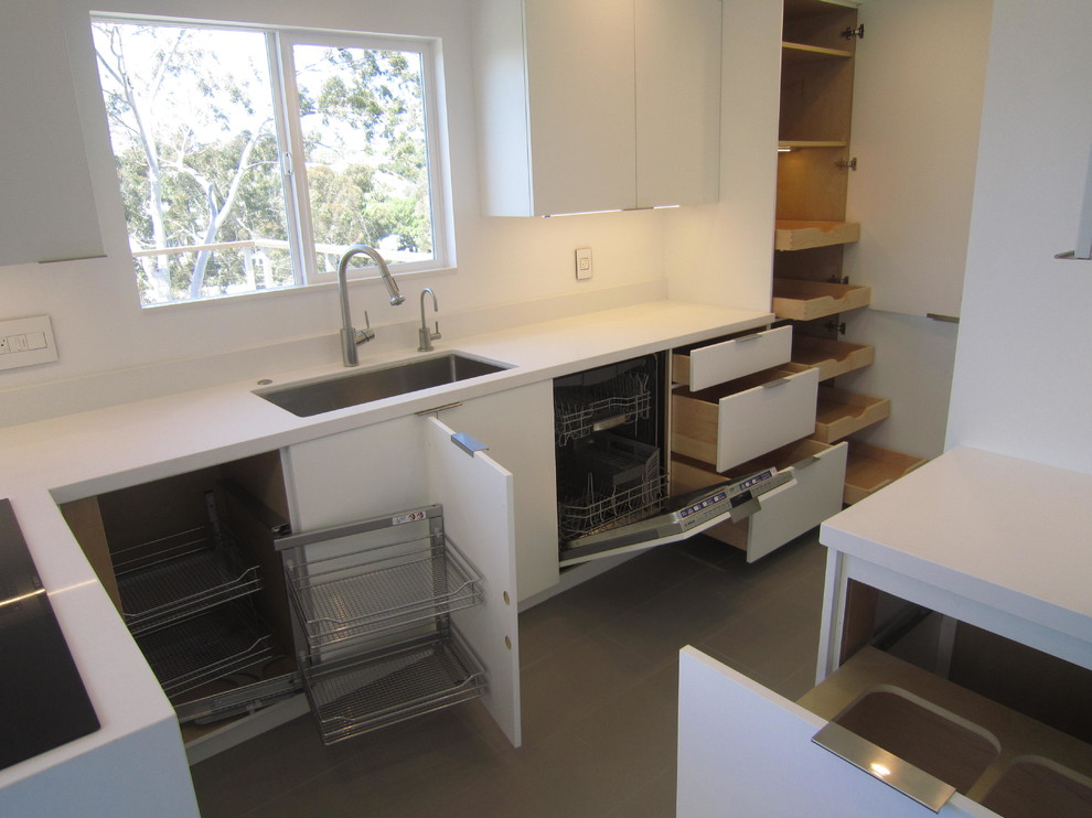 サンディエゴにあるお手頃価格の小さなミッドセンチュリースタイルのおしゃれなキッチン (シングルシンク、フラットパネル扉のキャビネット、白いキャビネット、珪岩カウンター、パネルと同色の調理設備、磁器タイルの床) の写真