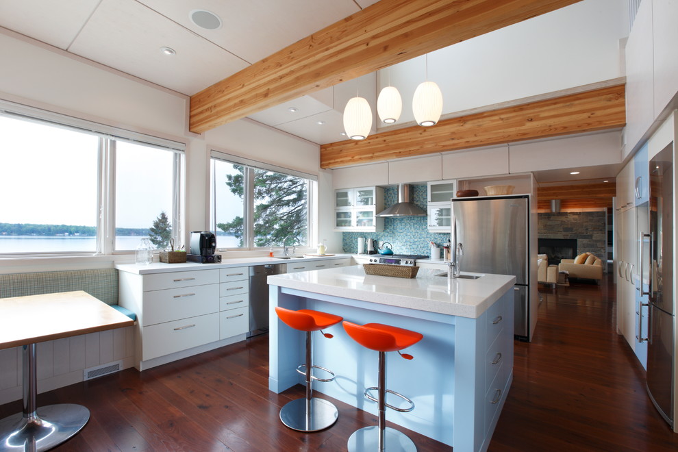 Photo of a small contemporary l-shaped kitchen/diner in Other with a submerged sink, flat-panel cabinets, white cabinets, blue splashback, glass tiled splashback, stainless steel appliances, dark hardwood flooring and an island.